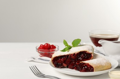 Delicious strudel with cherries, powdered sugar and mint on white table. Space for text