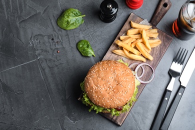 Juicy burger and French fries served on grey table, flat lay. Space for text