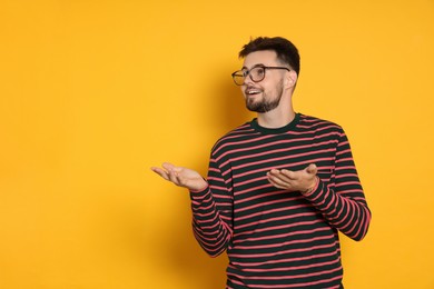 Photo of Handsome man in striped sweatshirt gesturing on yellow background