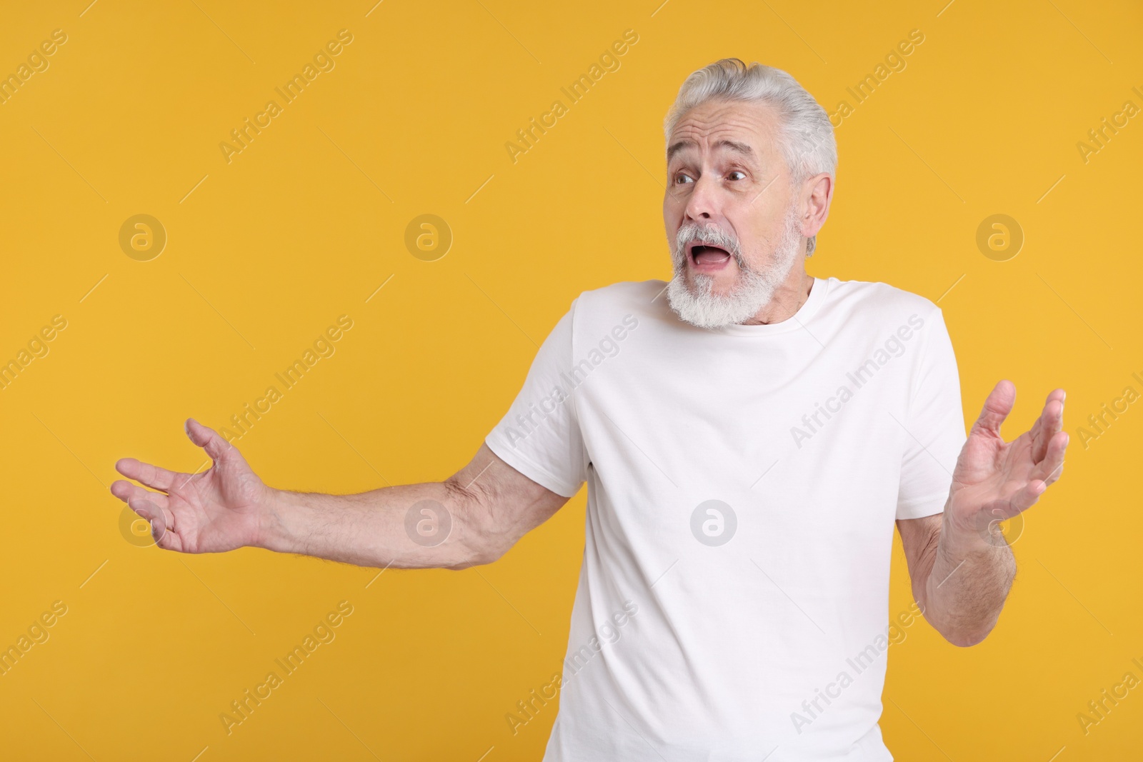 Photo of Portrait of surprised senior man on yellow background