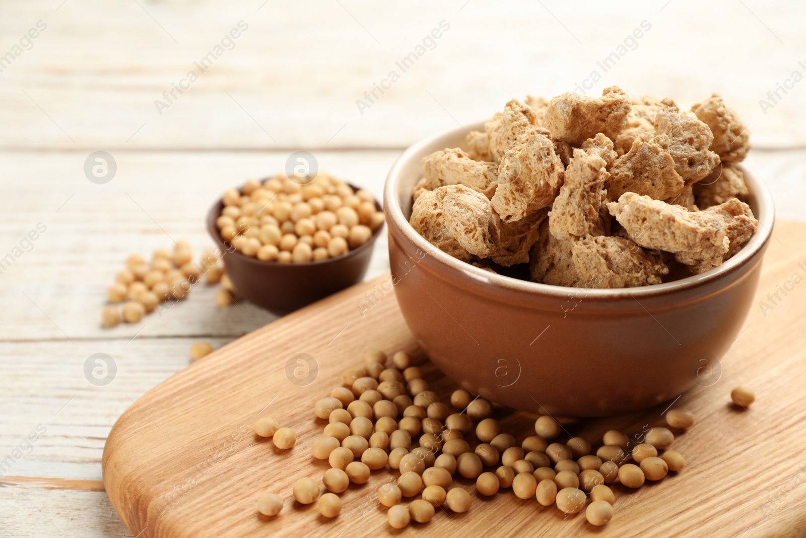 Photo of Dehydrated soy meat chunks and beans on white wooden table