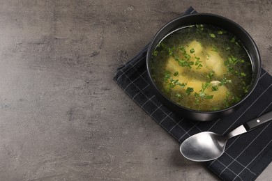 Delicious chicken soup with parsley and spoon on grey table, above view. Space for text
