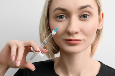 Photo of Cosmetologist with syringe on white background, closeup