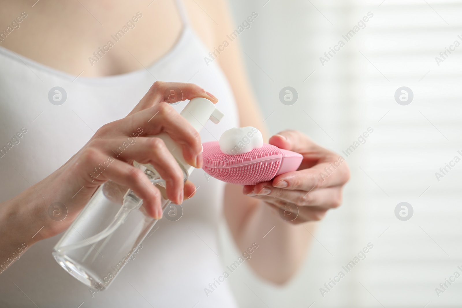 Photo of Washing face. Woman applying cleansing foam onto brush against light background, closeup. Space for text