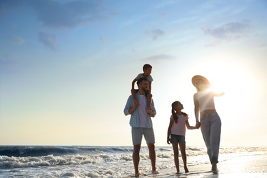 Photo of Happy family walking on sandy beach near sea