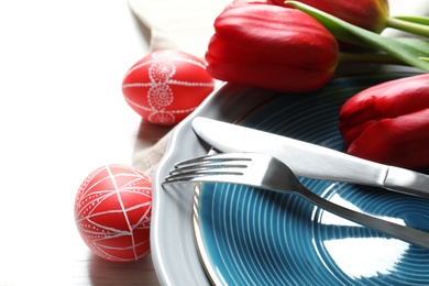 Festive Easter table setting with painted eggs on wooden background, closeup