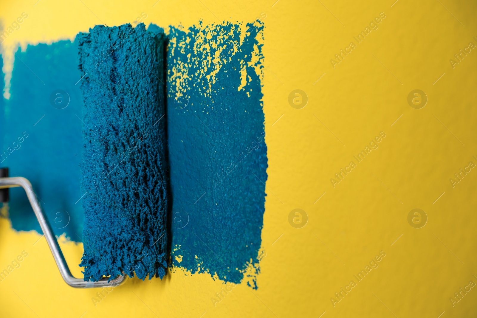 Photo of Painting yellow wall with blue dye, closeup view