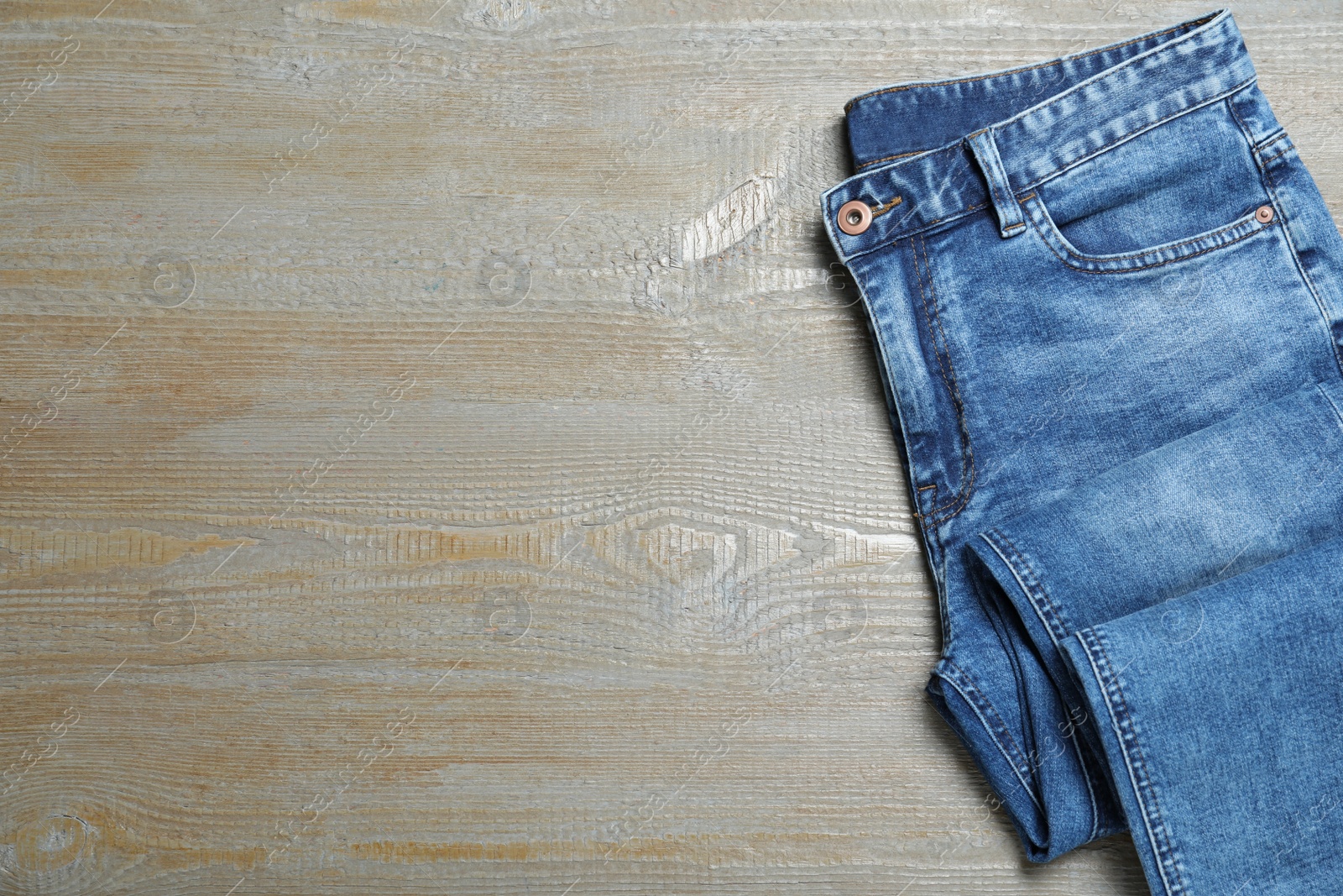 Photo of New stylish jeans on wooden background, top view. Space for text