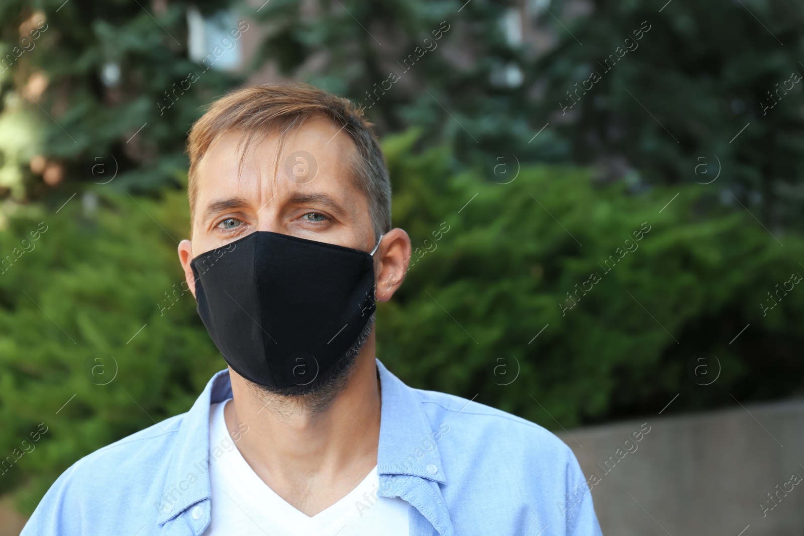 Photo of Man wearing handmade cloth mask outdoors, space for text. Personal protective equipment during COVID-19 pandemic