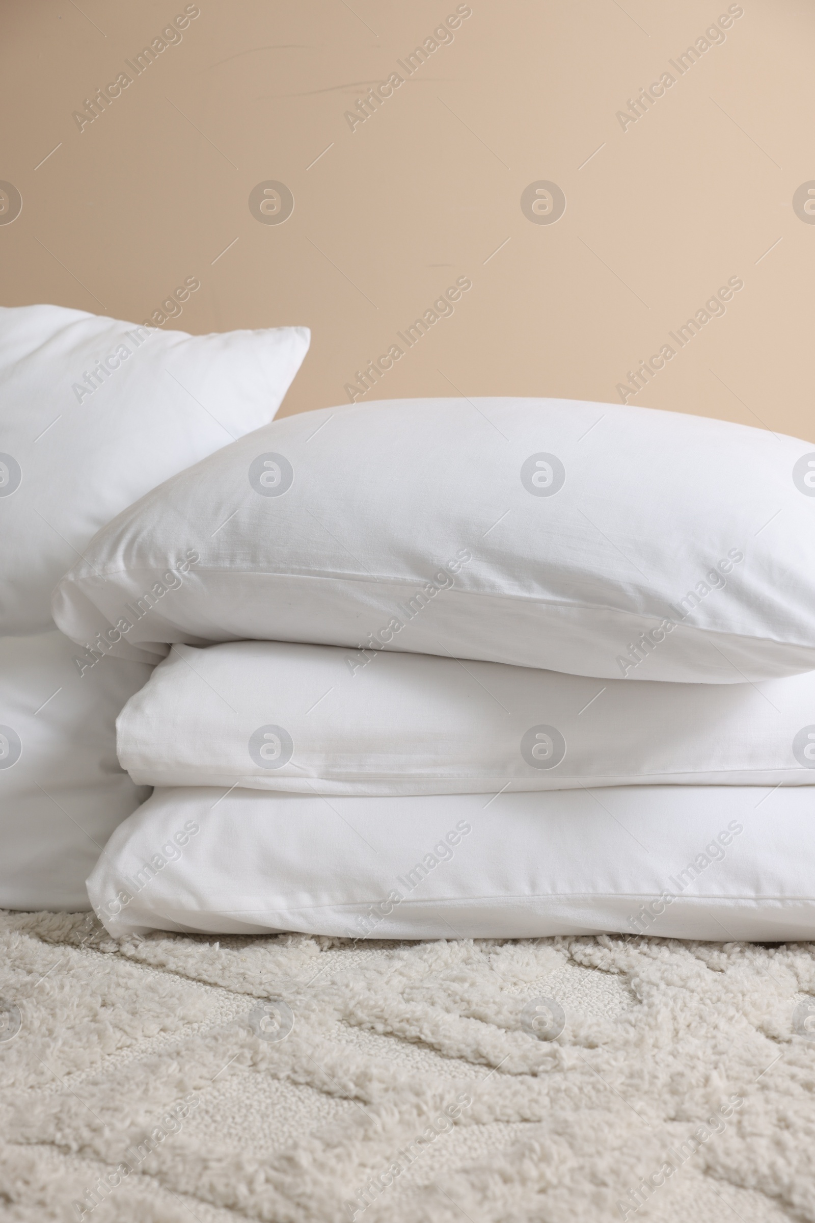 Photo of Soft white pillows near beige wall indoors