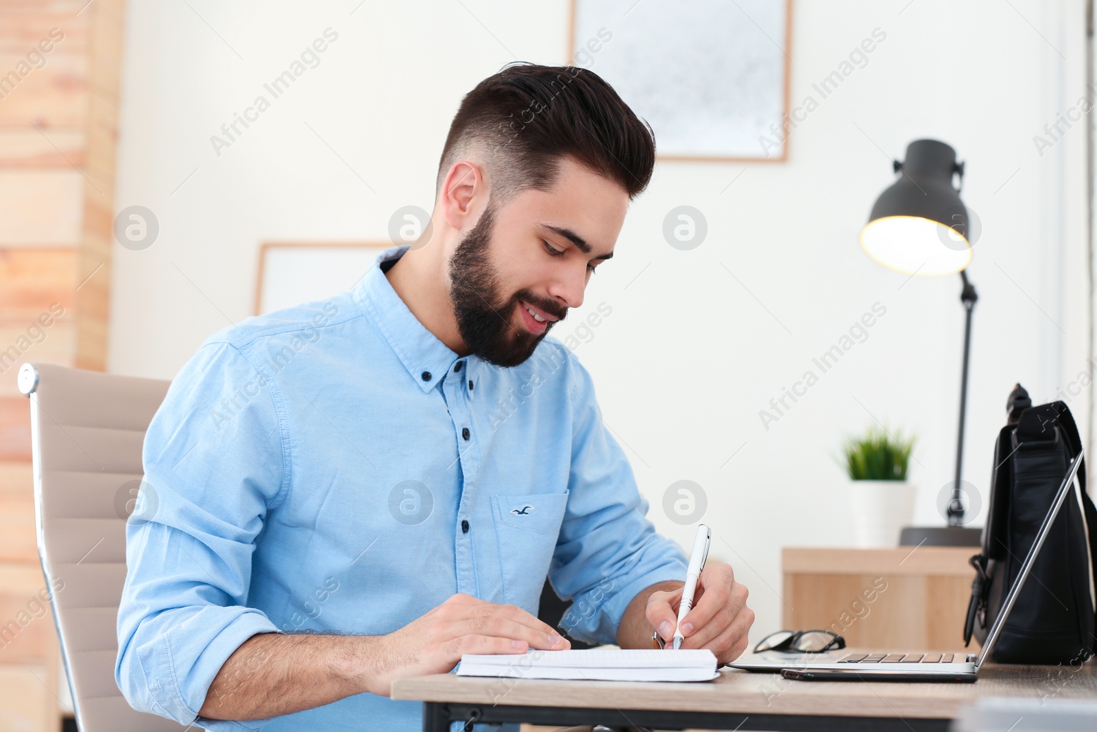 Photo of Handsome young man working at table in home office