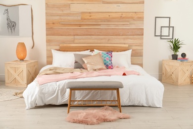 Photo of Stylish room interior with comfortable bed near wooden wall