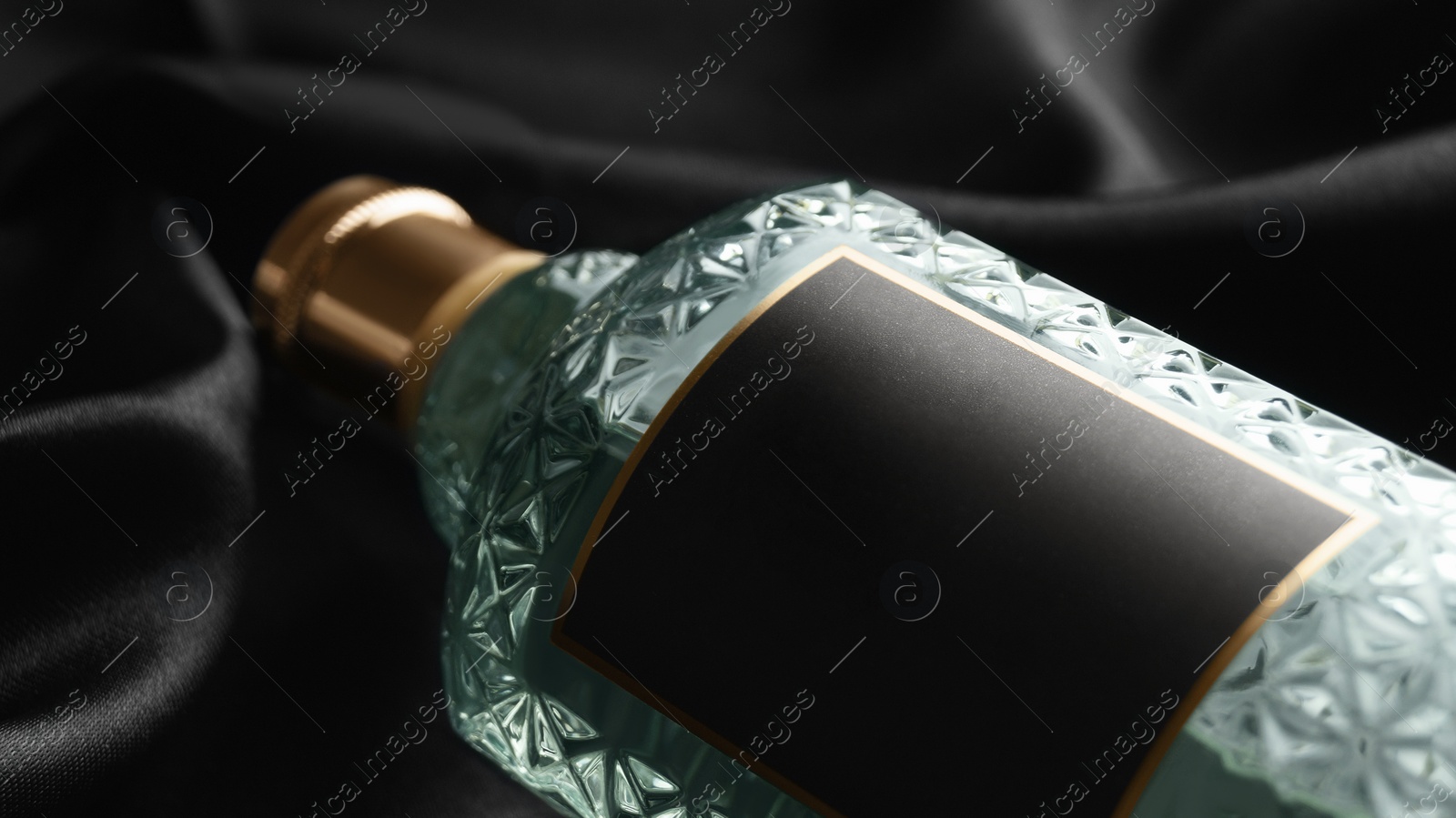 Photo of Luxury bottle of perfume on black silk, closeup