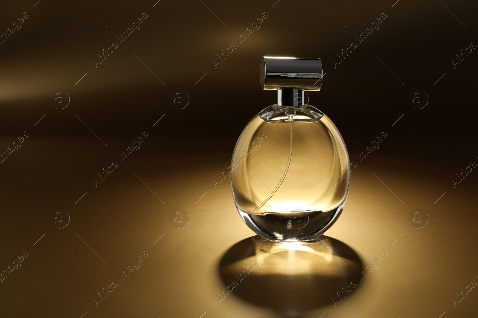 Photo of Luxury women's perfume. Sunlit glass bottle on golden background, space for text