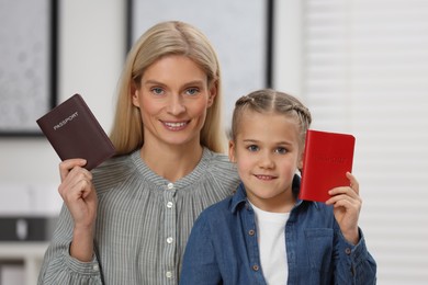 Immigration. Happy woman and her daughter with passports indoors