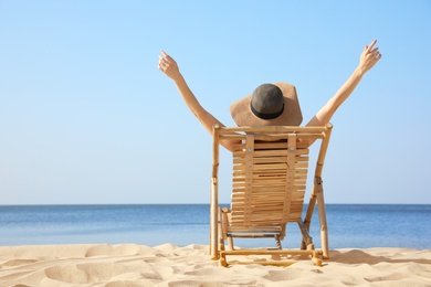 Photo of Young woman relaxing in deck chair on sandy beach