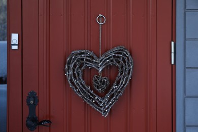 Photo of Beautiful heart shaped wreath made of twigs hanging on door
