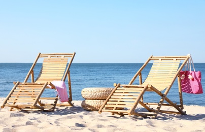 Photo of Empty wooden sunbeds and beach accessories on sandy shore