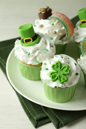 Photo of St. Patrick's day party. Tasty festively decorated cupcakes on white table, closeup