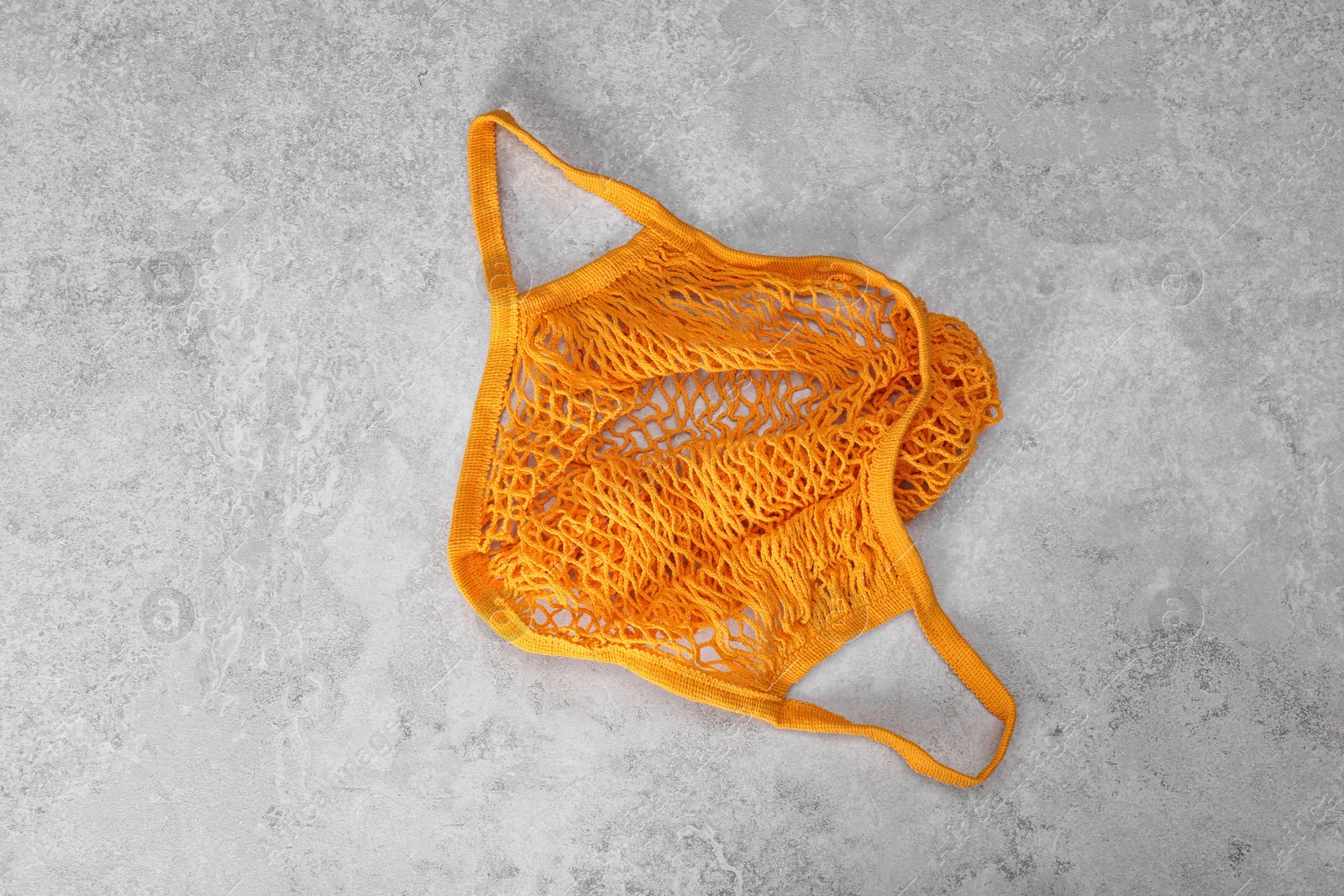 Photo of Orange net bag on light grey table, top view