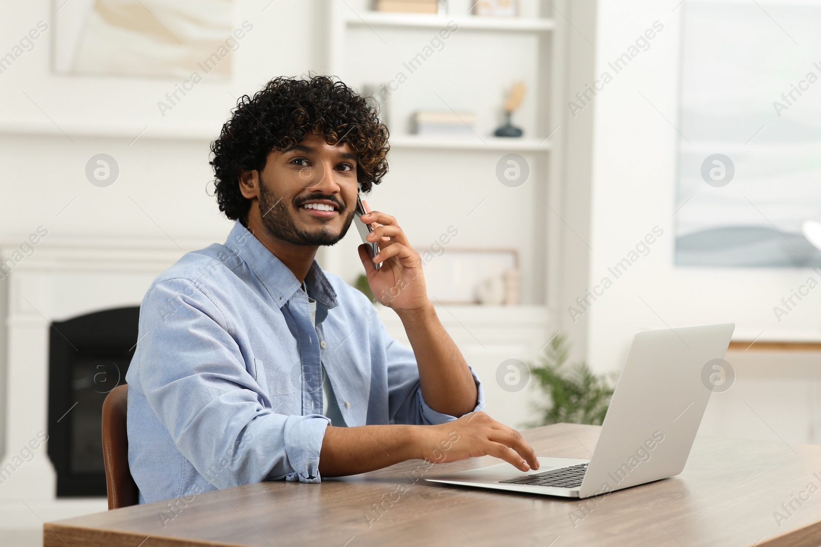 Photo of Handsome smiling man talking on smartphone in room, space for text