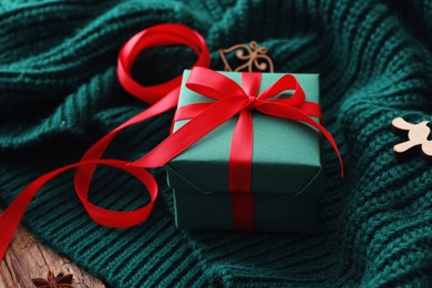 Photo of Christmas gift box on green knitted cloth, closeup