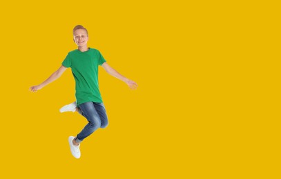 Image of Happy boy jumping on golden background, space for text