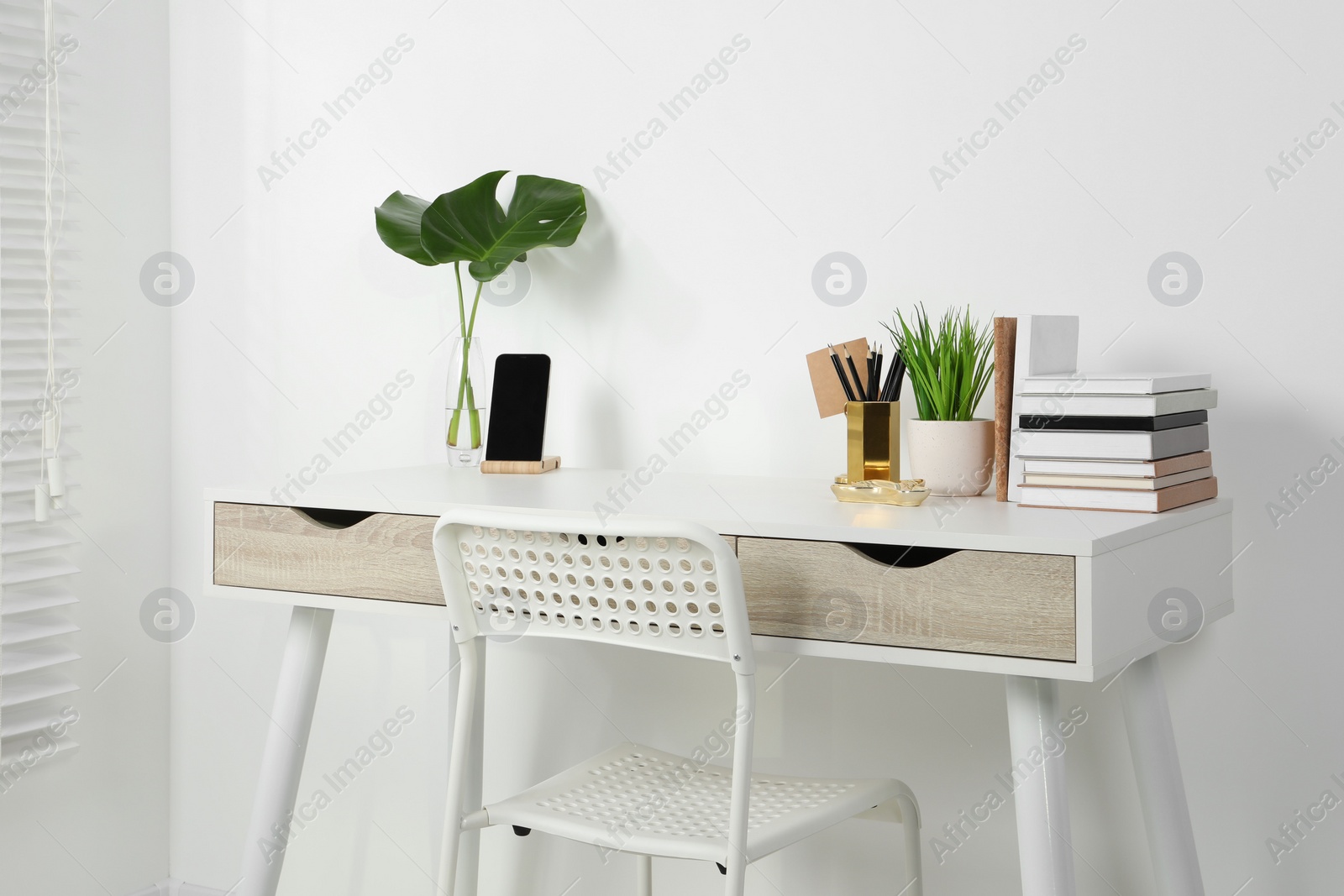 Photo of Comfortable workplace with white desk near wall indoors