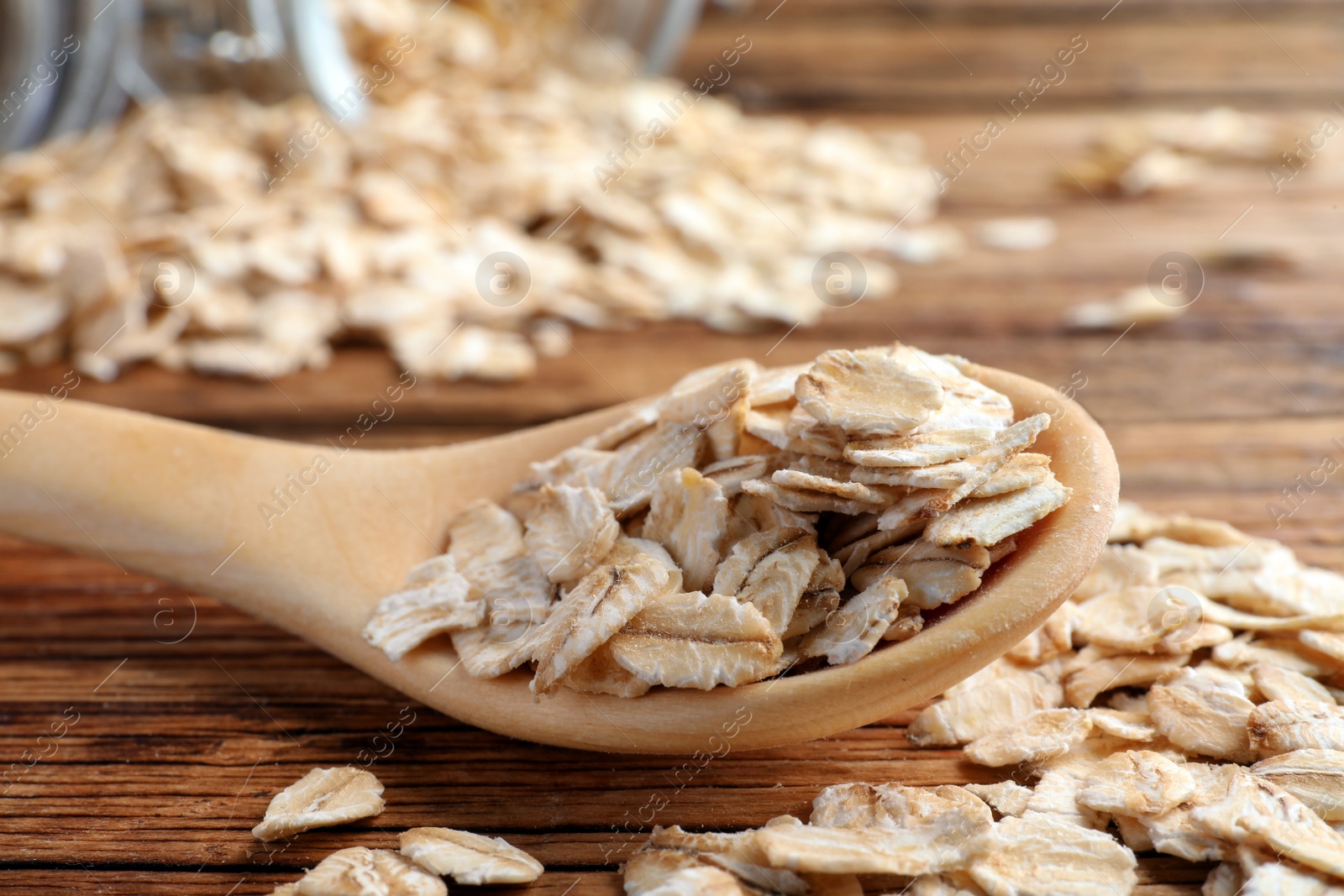 Photo of Raw oatmeal and spoon on wooden table, closeup