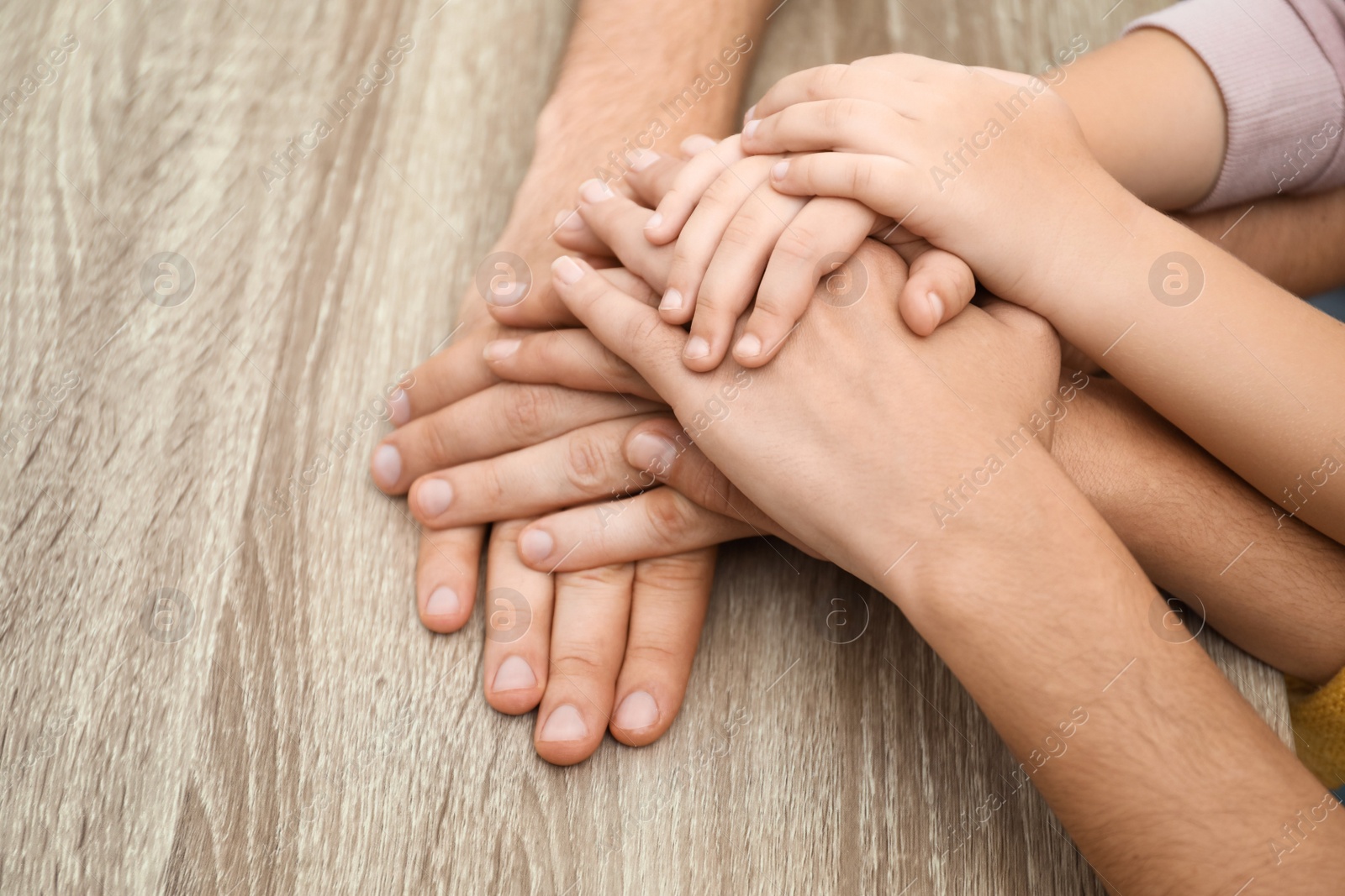 Photo of Happy family holding hands at wooden table, closeup view