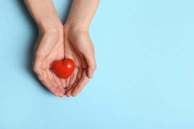 Photo of Woman holding heart on blue background, top view with space for text. Donation concept