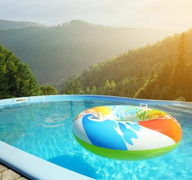 Image of Colorful inflatable ring floating in outdoor swimming pool at luxury resort and beautiful view of mountains on sunny day