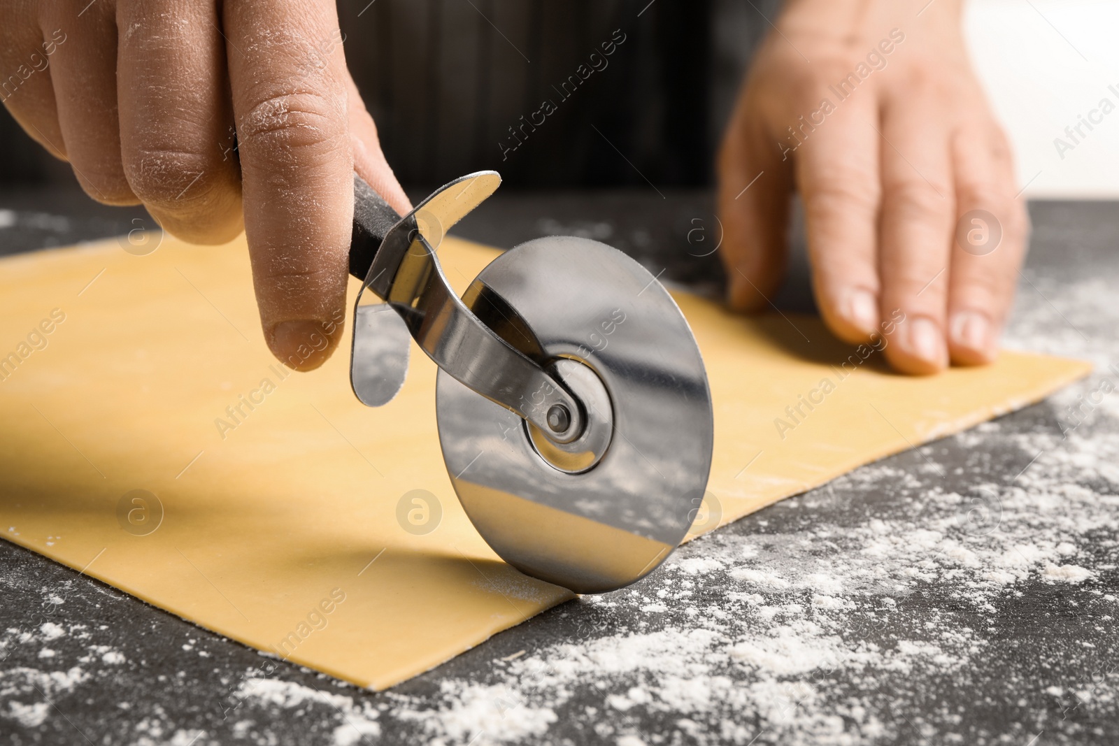 Photo of Woman making pasta at grey table, closeup