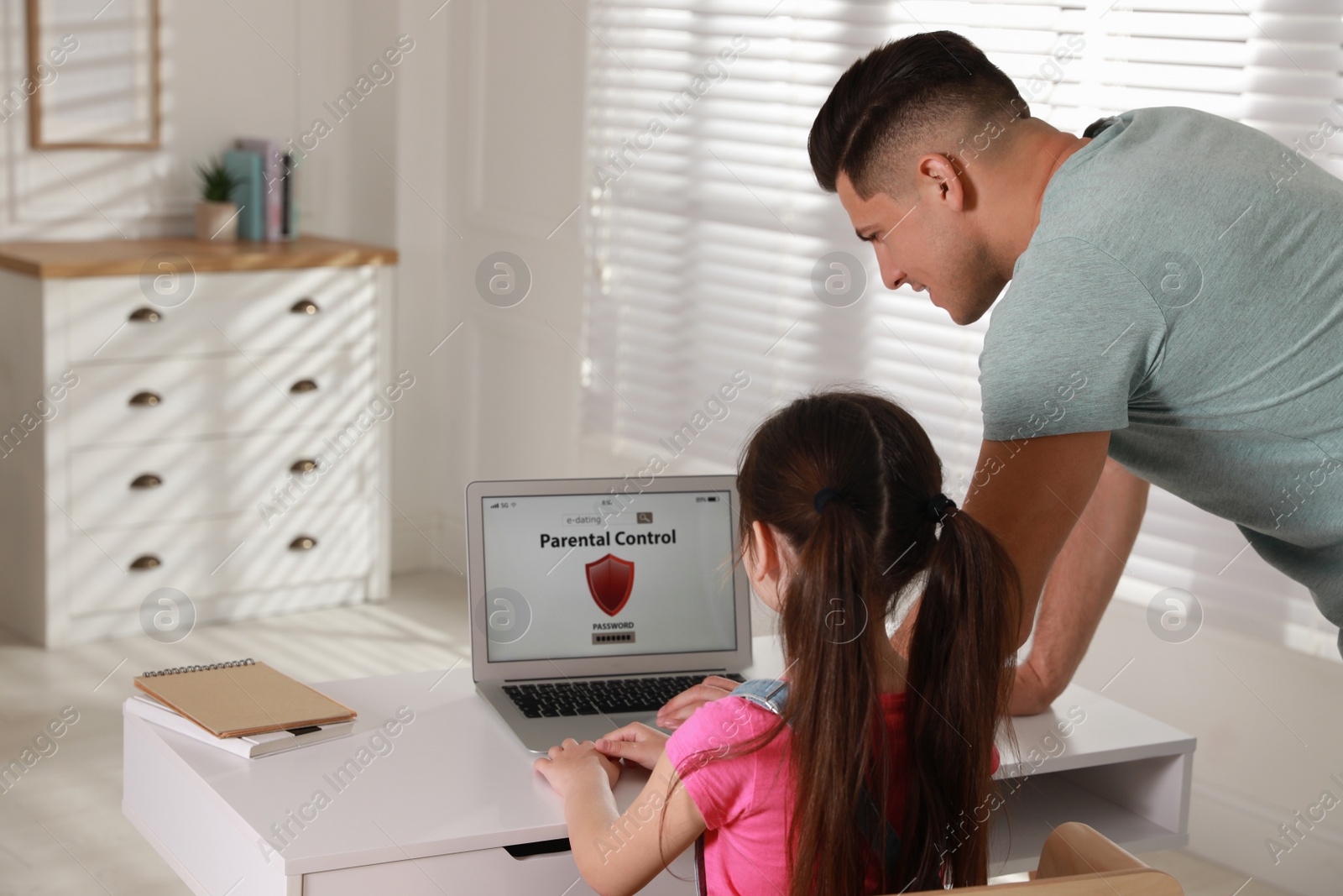 Photo of Father installing parental control app on laptop to ensure his child's safety at home