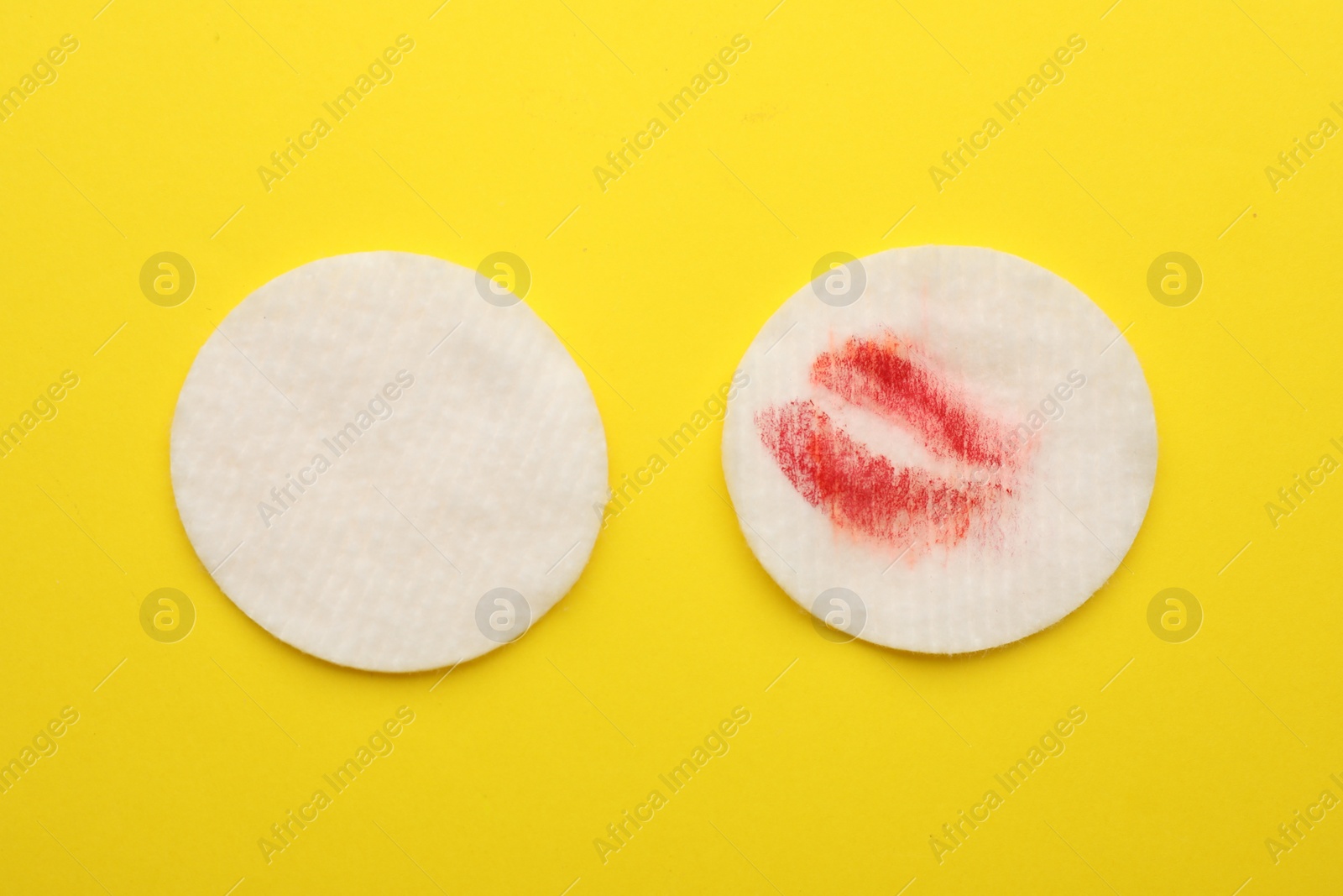 Photo of Clean and dirty cotton pads after removing makeup on yellow background, flat lay