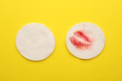 Clean and dirty cotton pads after removing makeup on yellow background, flat lay