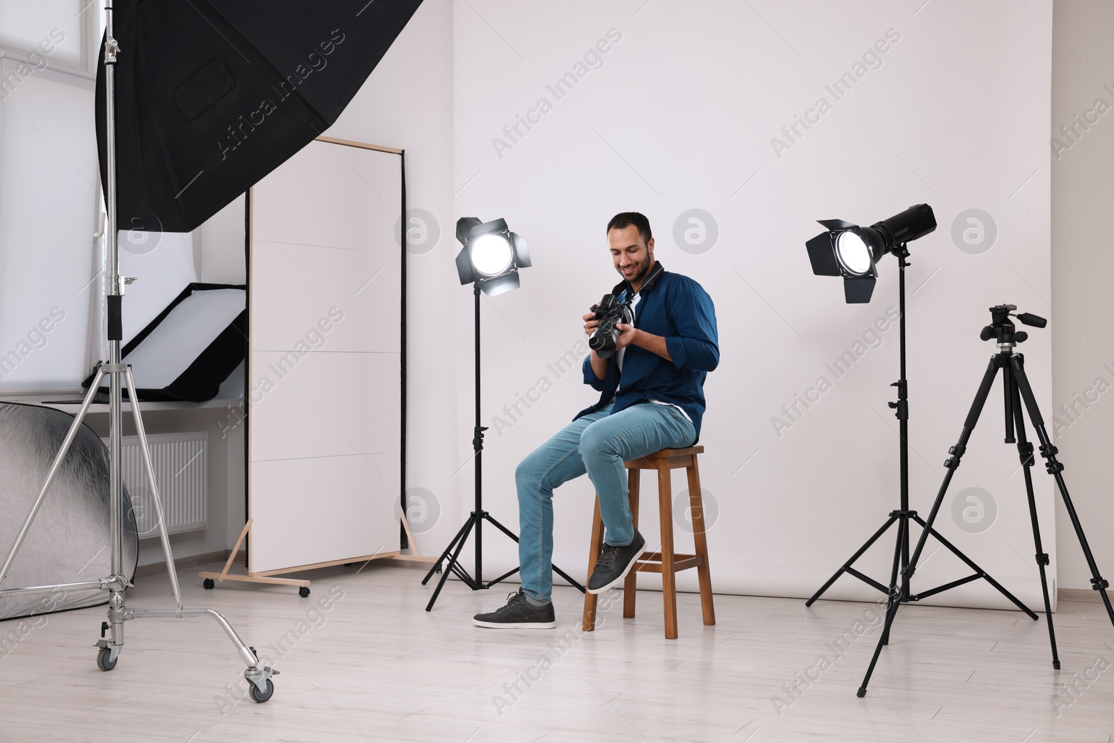 Photo of Young professional photographer with camera in modern photo studio