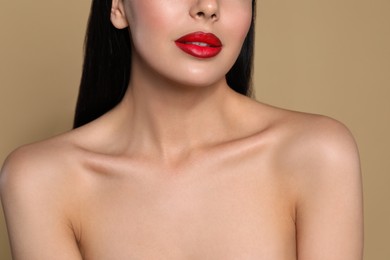Photo of Young woman wearing beautiful red lipstick on beige background, closeup