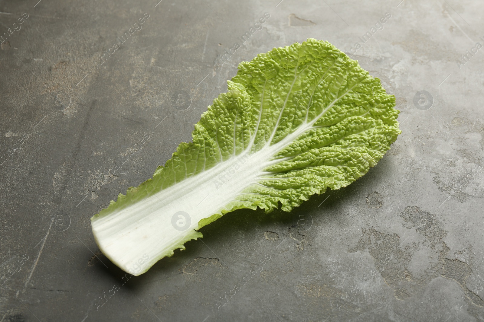 Photo of Fresh Chinese cabbage leaf on gray textured table