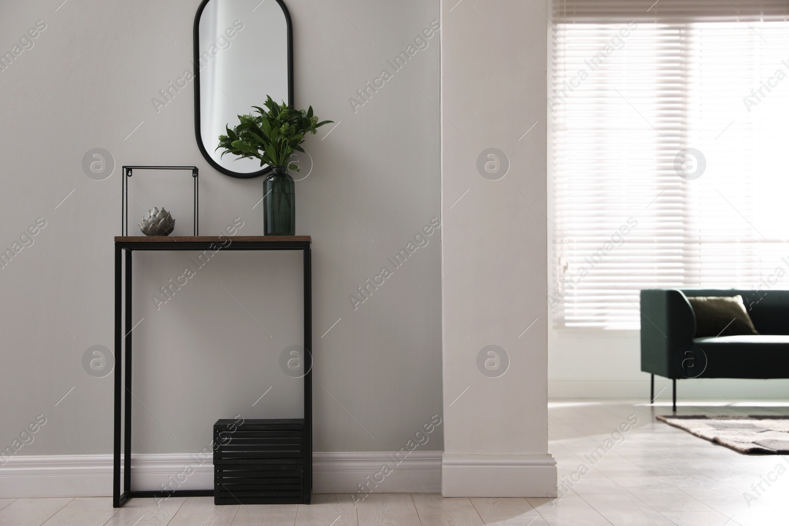 Photo of Console table with decor and mirror on light wall in hallway. Interior design