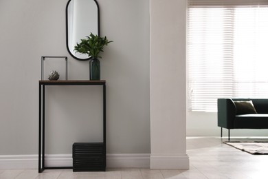 Console table with decor and mirror on light wall in hallway. Interior design