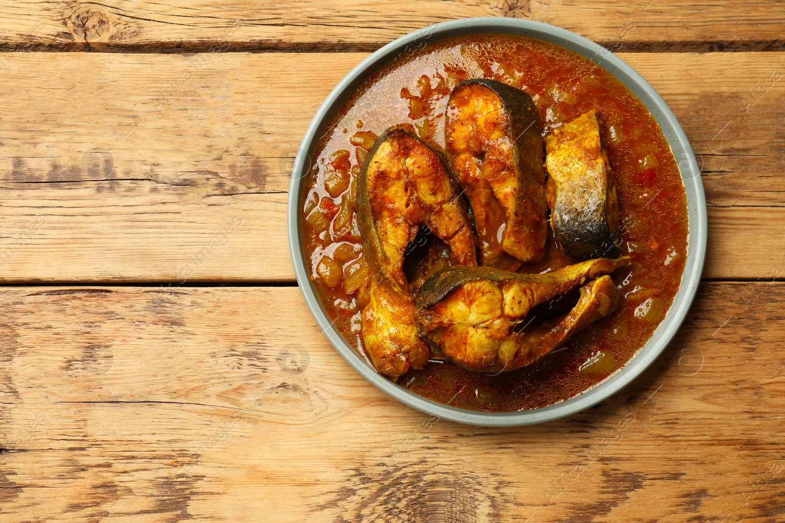 Photo of Tasty fish curry on wooden table, top view. Space for text. Indian cuisine