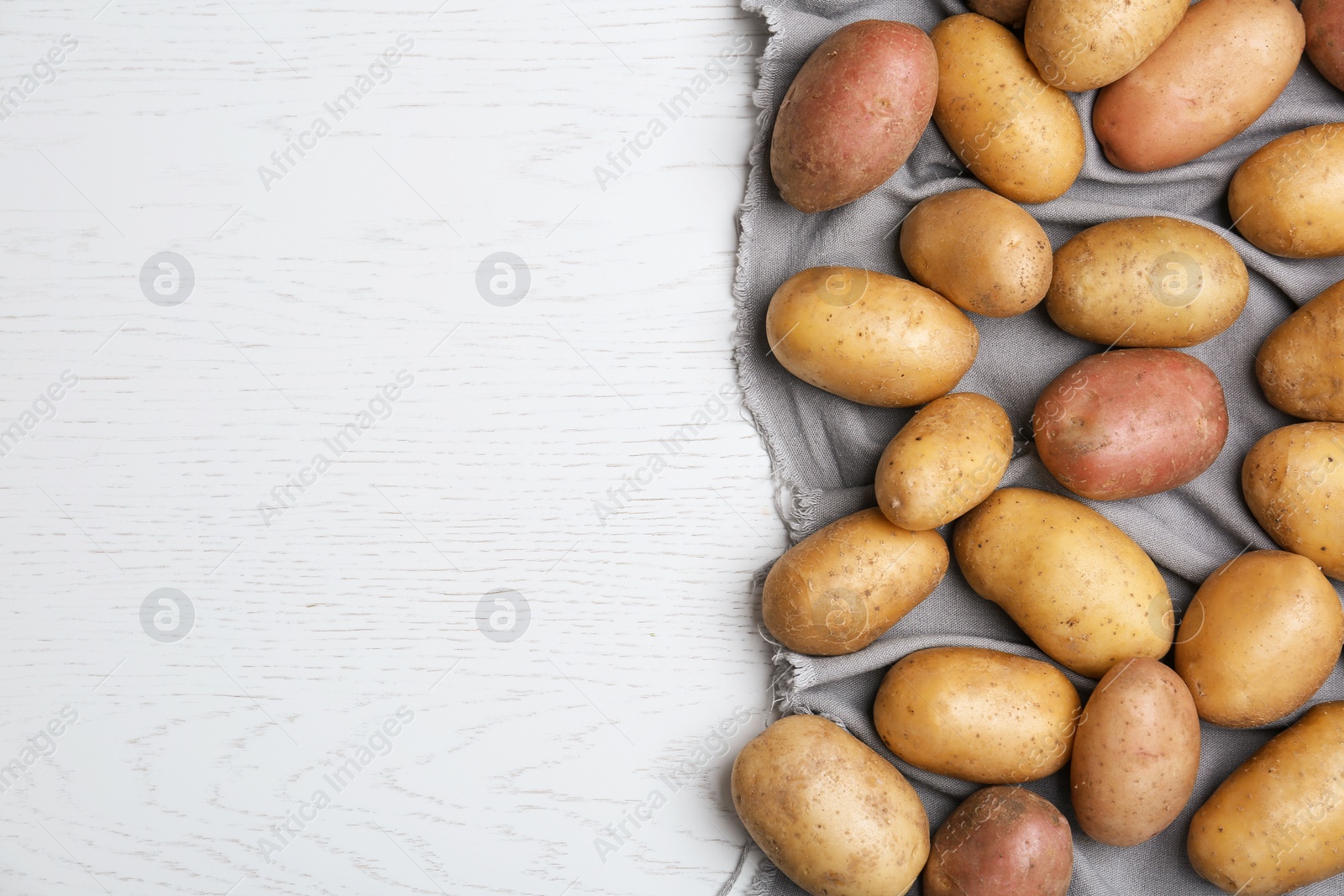 Photo of Fresh ripe organic potatoes on white wooden background, top view