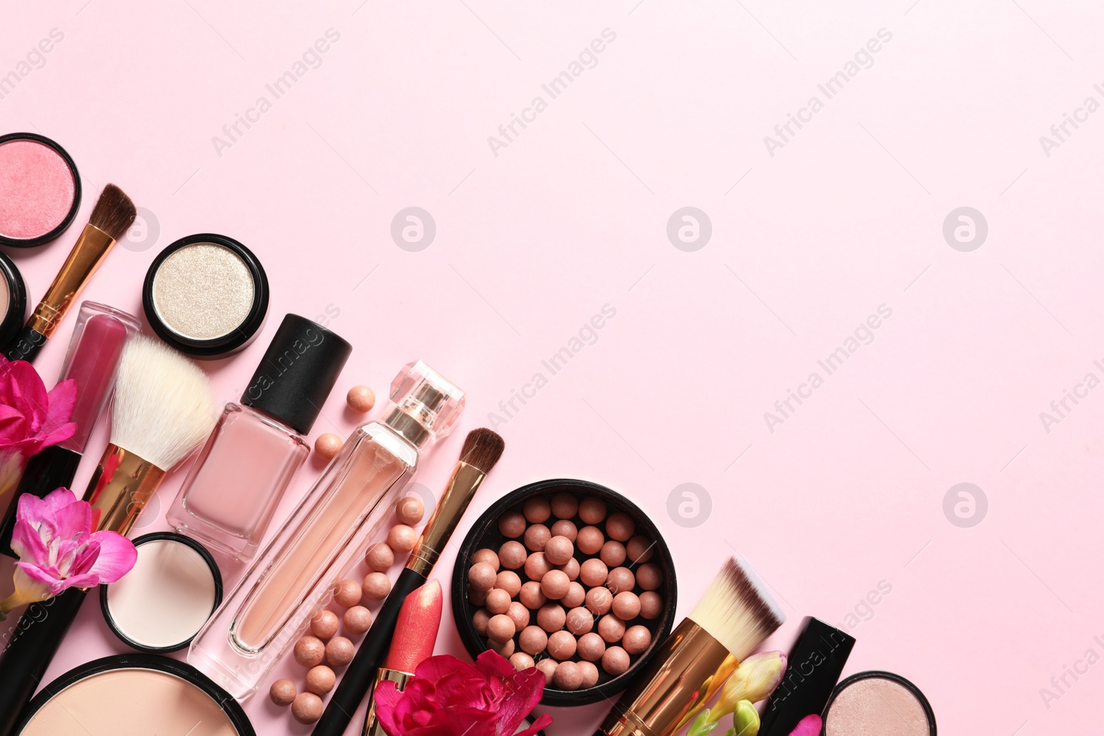 Photo of Different makeup products with flowers on color background. Space for text