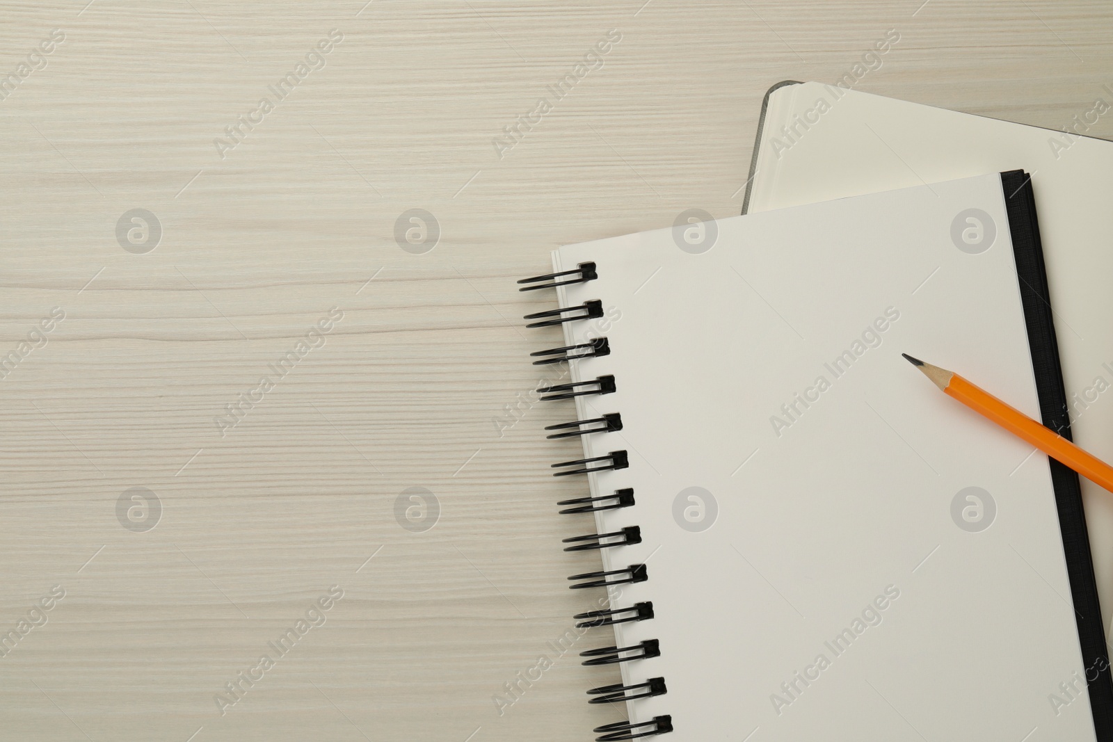 Photo of Notebooks and pencil on white wooden table, top view. Space for text