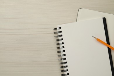 Notebooks and pencil on white wooden table, top view. Space for text