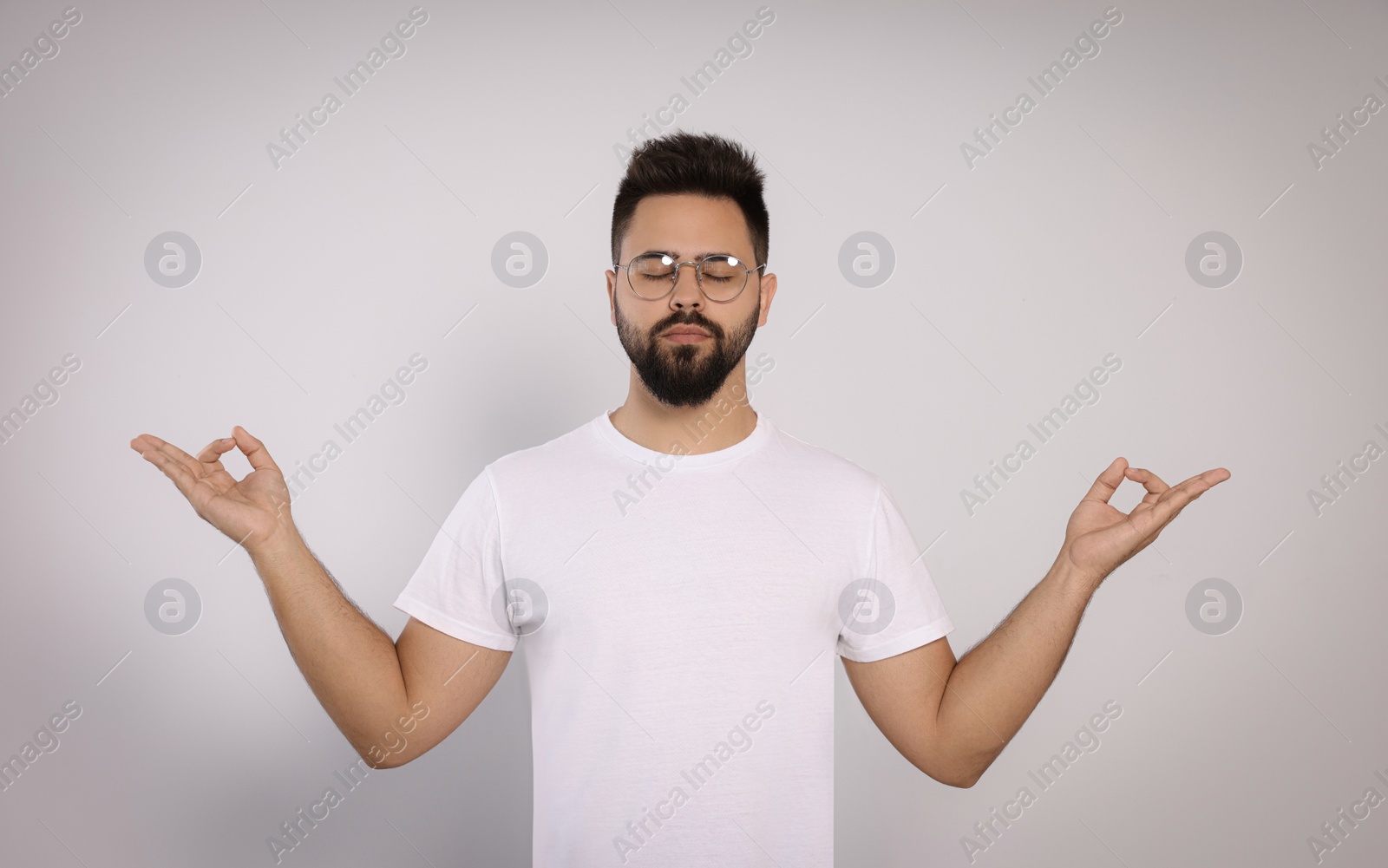 Photo of Young man meditating on white background. Zen concept