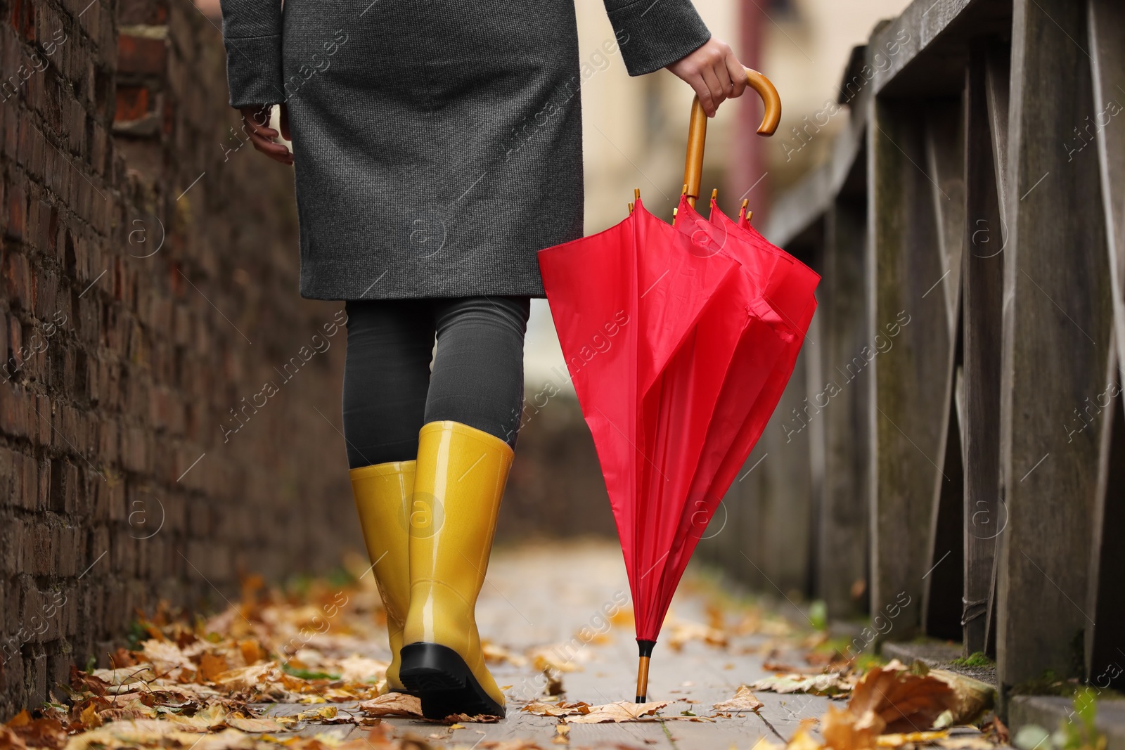 Photo of Woman with red umbrella walking on city street, closeup