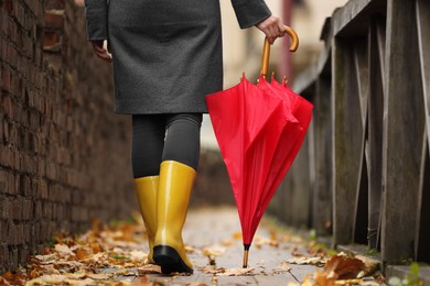 Photo of Woman with red umbrella walking on city street, closeup