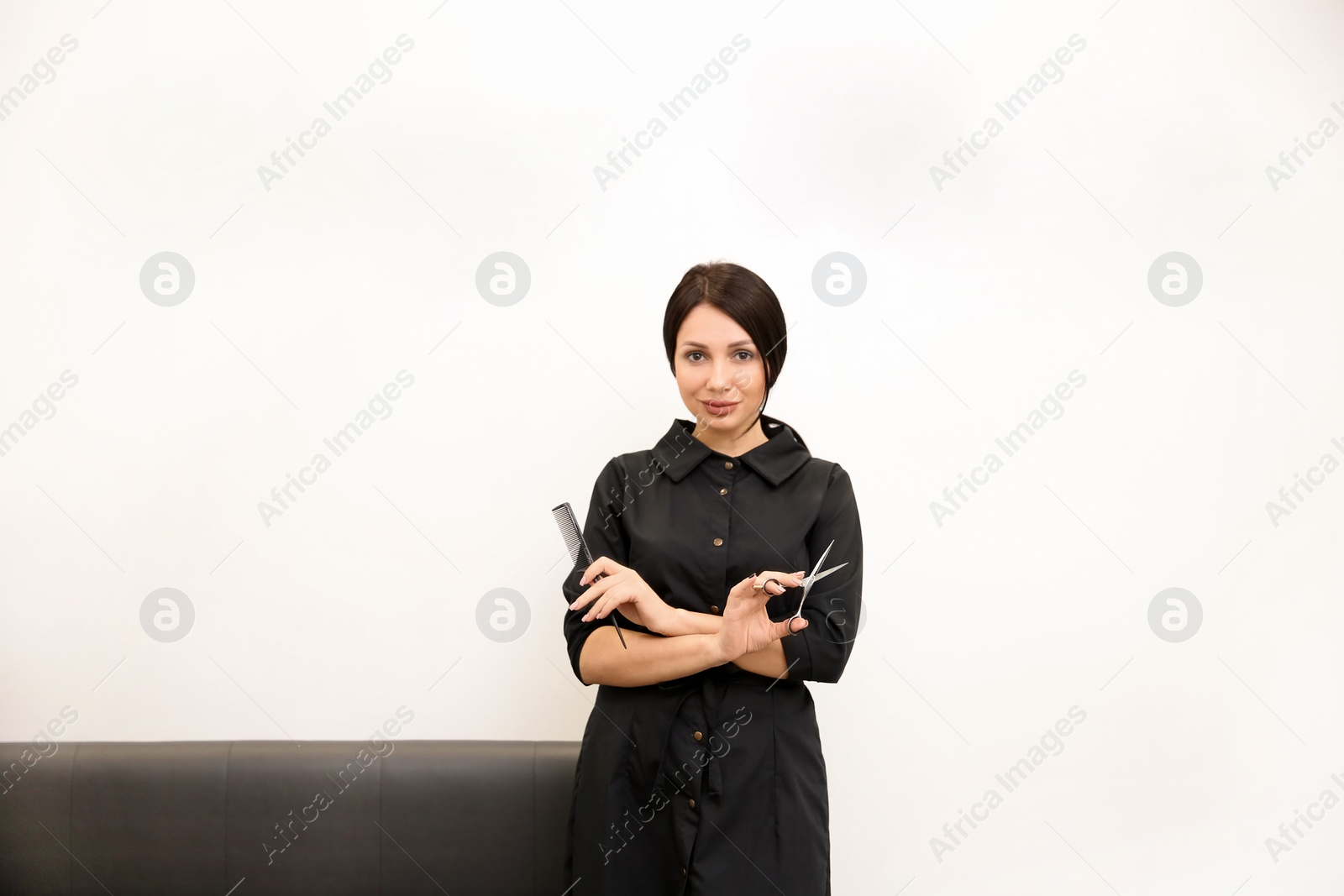 Photo of Professional female hairdresser with comb and scissors in salon